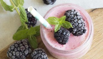Enjoy a refreshing blackberry smoothie topped with fresh mint leaves, perfect for a summer treat.