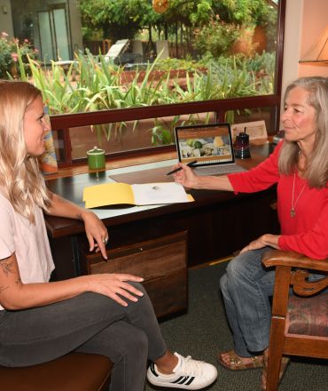 Crop anonymous African American man in casual clothes sitting on sofa and talking to female psychologist during psychotherapy session in modern studio